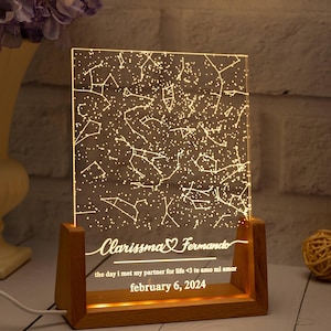 Op de afbeelding: Een rechthoekig acryl nachtlampje met een oplichtend sterrenkaartontwerp. De voet is gemaakt van licht hout en houdt het acrylpaneel vast. De tekst luidt: Clarissma & Fernando, the day i met my partner for life <3 te amo mi amor, february 6, 2024.