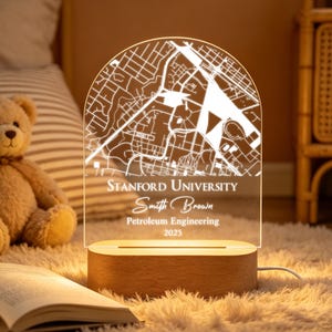 May include: A personalized LED night light with a map of Stanford University. The light is engraved with the text "Stanford University", "Smith Brown", "Petroleum Engineering", and "2025". The base is made of wood.