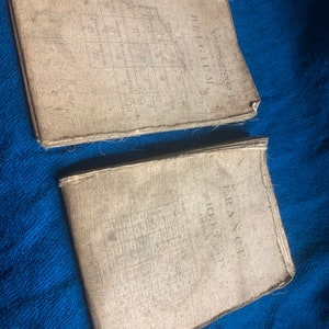 May include: Two vintage, worn, paper-covered books with the titles "VALENCIENNES 12 EDITION 2 BELGIUM" and "FRANCE SHEET T EDITION 2" printed on the covers.