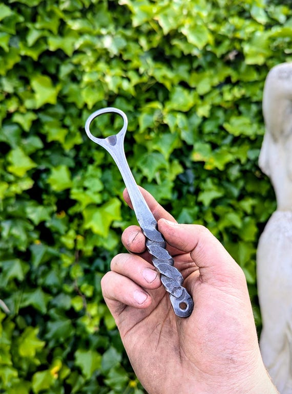 A blacksmith actually hammer-twisted iron into a bottle opener — you can see the forge marks, and no two are alike.