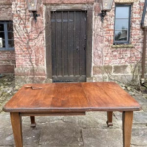 May include: A dark wood extendable dining table with four legs. The table is set up in a square shape and is sitting on a stone patio.