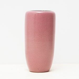 Könnte beinhalten: Eine hohe, zylindrische Vase in Staubrosa. Die Vase hat eine leicht strukturierte Oberfläche und eine glatte, abgerundete Oberseite. Der Innenraum ist dunkler violett. Diese dekorative Vase eignet sich für Blumengestecke.