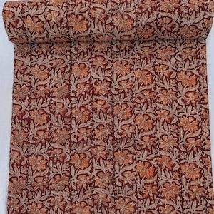 May include: A rectangular quilted throw blanket featuring a deep maroon background with a repeating pattern of orange and cream-colored floral motifs. The fabric displays vertical stitching lines throughout, creating a textured, layered appearance.