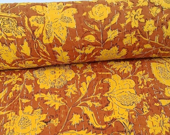 May include: A yellow and brown floral kantha quilt with a repeating pattern of flowers and leaves. The quilt is made of cotton and is hand-stitched.