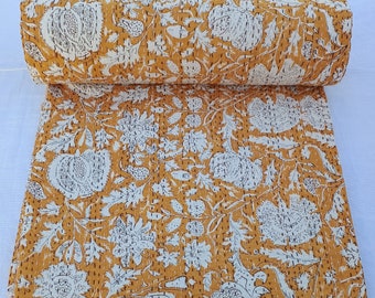 May include: A yellow and white kantha quilt with a floral pattern. The quilt is rolled up and the fabric is visible.