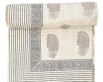 May include: A folded cotton quilt featuring an off-white base with dark gray block-printed paisley motifs and geometric border patterns. The textile displays visible running stitch kantha embroidery throughout, creating a textured surface finish.