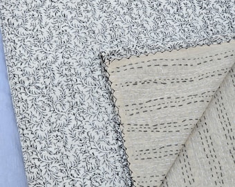 May include: Cream-colored quilt with a black, swirling floral pattern. The reverse side is a solid cream color with horizontal black stitching. The edges are finished with black stitching. This handmade quilt is suitable for a bed or sofa.