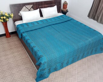 Könnte beinhalten: Eine türkisfarbene Tagesdecke mit einem sich wiederholenden Muster aus kleinen dunkelblauen Punkten und einem floralen Bordürendesign. Die Tagesdecke ist ordentlich auf einem Bett mit weißen Kissen und einem Holz-Kopfteil angeordnet. Thema: Wohnkultur.