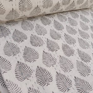 May include: White fabric with a repeating pattern of gray leaf designs. The fabric is folded in half, showing the pattern on both sides.
