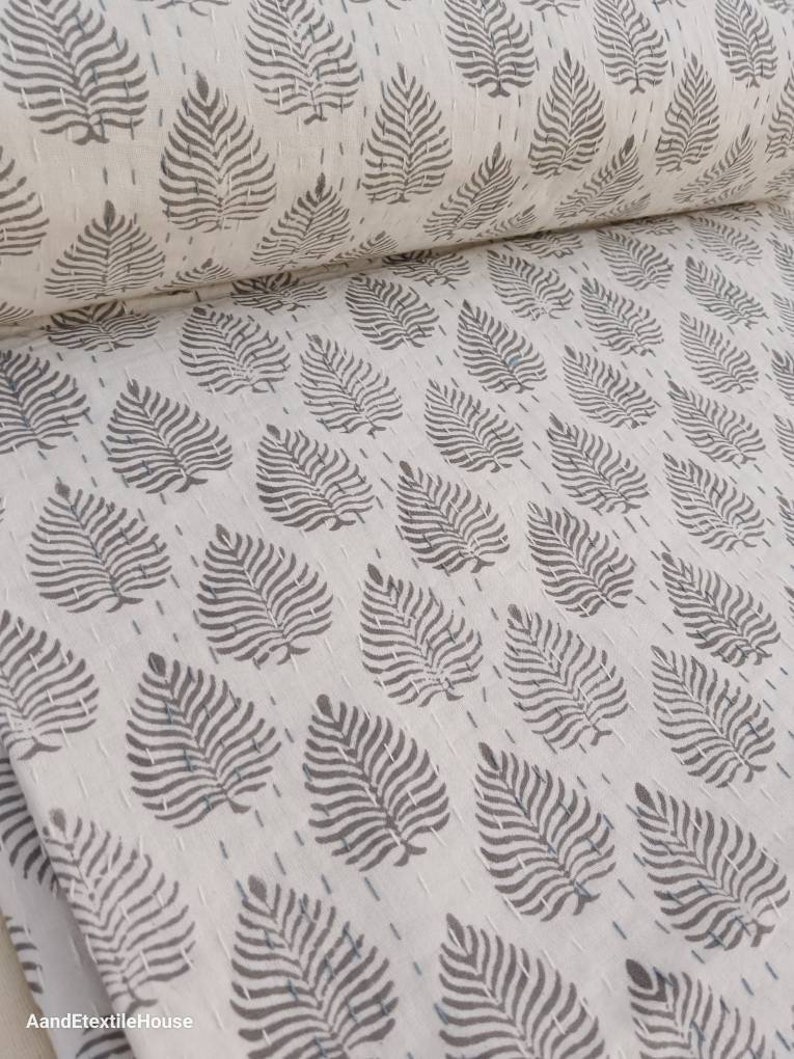 May include: White fabric with a repeating pattern of gray leaf designs. The fabric is folded in half, showing the pattern on both sides.