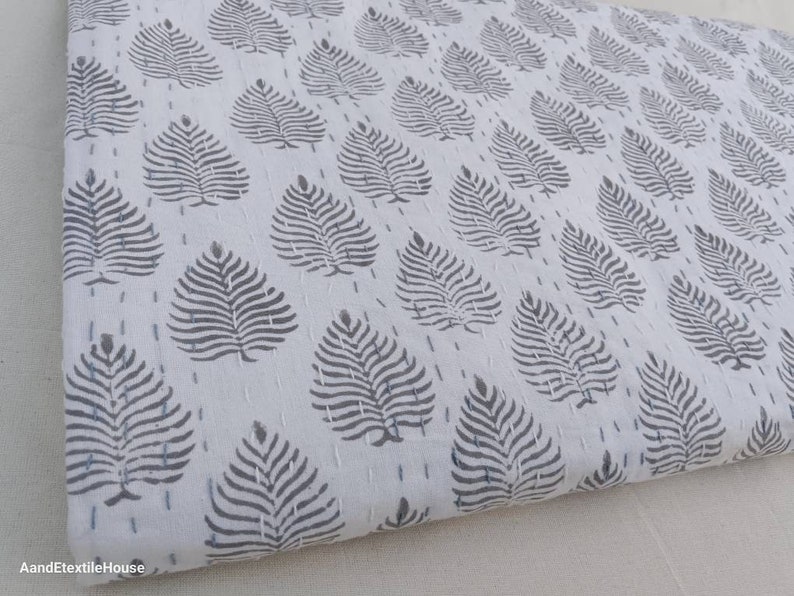 May include: White cotton fabric with a repeating pattern of gray leaf designs. The fabric is folded and has a subtle texture.