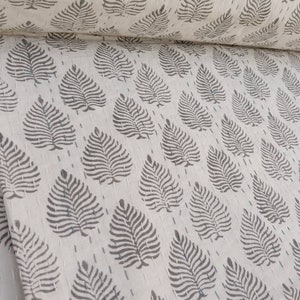 May include: White cotton fabric with a repeating pattern of gray leaf prints. The fabric is folded in half and the pattern is visible on both sides.