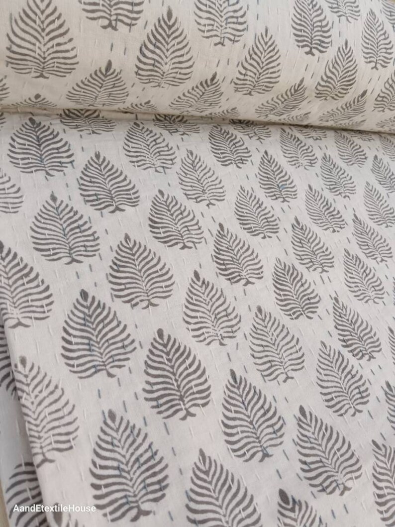 May include: White cotton fabric with a repeating pattern of gray leaf prints. The fabric is folded in half and the pattern is visible on both sides.