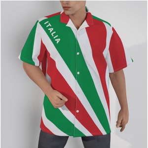 Può includere: Camicia a maniche corte con un design a righe diagonali nei colori della bandiera italiana: verde, bianco e rosso. La parola "ITALIA" è stampata in bianco su una striscia verde. La camicia ha un colletto classico.
