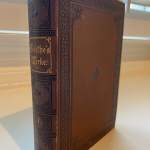 May include: A brown leather-bound book with gold lettering on the spine that reads "Goethe's Werke" and the number "7".