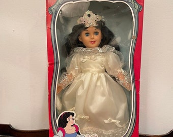 May include: A vintage Snow White doll in a white dress with a crown, packaged in a red box with the text "Snow White in the Land of Doom".