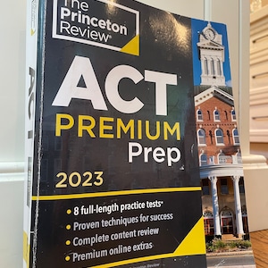May include: A black and yellow book titled "The Princeton Review ACT Premium Prep 2023" with a picture of a red brick building with a clock tower on the cover. The book features 8 full-length practice tests, proven techniques for success, complete content review, and premium online extras.