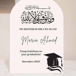 May include: A graduation keepsake with an arched top, featuring Arabic calligraphy and the English text "MY SUCCESS IS ONLY BY ALLAH." Below is the name "Maria Ahmed," and the message "Congratulations on your graduation!" dated November 2025. A silhouette of a graduate is on the right.