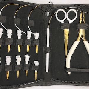 May include: A black zippered case containing jewelry-making tools. The kit includes white-handled pliers and scissors with gold blades, white and gold wire, white plastic tools, and gold-colored pins. The tools are secured with black elastic bands.