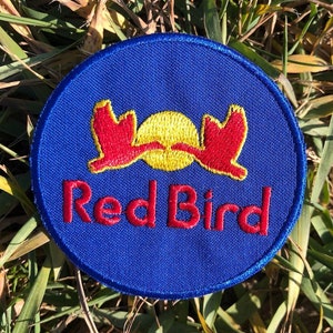 May include: A blue circular patch with a red bird logo and the text "Red Bird" in red embroidery.