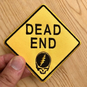May include: Yellow diamond-shaped patch with black border and text "DEAD END". A black and white skull with a lightning bolt is in the center of the patch.