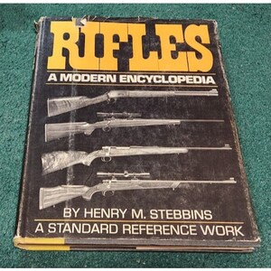 May include: A black book with the title "Rifles: A Modern Encyclopedia" in yellow letters. The book cover features images of four rifles and the author's name, Henry M. Stebbins. The book is described as "A Standard Reference Work".