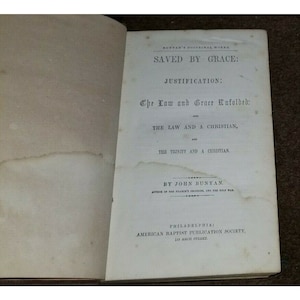 May include: A book cover with the title "Saved by Grace: Justification: The Law and Grace Unfolded: The Law and a Christian, and The Trinity and a Christian." by John Bunyan, author of "The Pilgrim's Progress" and "The Holy War". Published by the American Baptist Publication Society in Philadelphia.