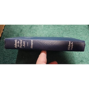 Puede incluir: Un libro de tapa dura azul titulado "Arithmetic for the Practical Man" de Thompson, publicado por D. Van Nostrand Company, Inc.
