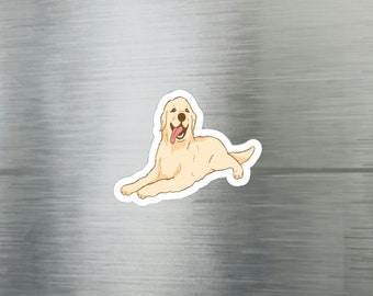 Op de afbeelding: Een sticker met een cartoon illustratie van een Golden Retriever hond die ligt met zijn tong uit. De hond is lichtbruin met een witte omtrek. De sticker zit op een zilveren koelkastdeur.