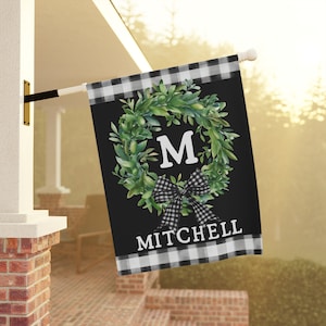 May include: Black and white checkered garden flag with a green wreath and a white letter M in the center. The wreath has a black and white checkered bow. The text "MITCHELL" is at the bottom of the flag.