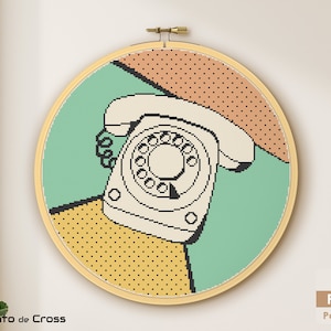 May include: A cross-stitch pattern of a vintage rotary phone in a pop art style with a green, yellow, and orange background. The pattern is framed in a wooden hoop.