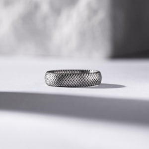 Può includere: Un anello d'argento con un motivo testurizzato a pelle di serpente.
