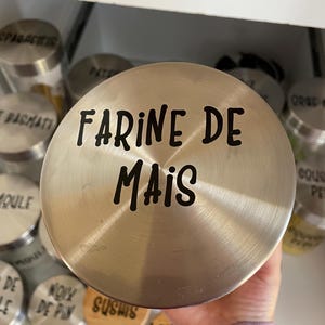 以下が含まれることがあります： 「FARINE DE MAIS」と黒のラベルが付いた銀色の金属容器です。