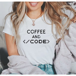 May include: A white t-shirt with the text "COFFEE AND </CODE>" printed on the front.