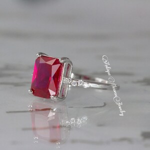 Pu&ograve; includere: Un anello d'argento con una grande pietra rossa di forma quadrata e pietre trasparenti pi&ugrave; piccole sulla fascia.