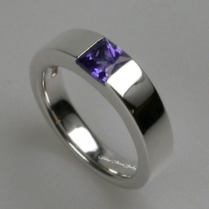 May include: A silver band ring with a square purple gemstone set in the centre. The ring is engraved with "Salope Maria Jewelry".