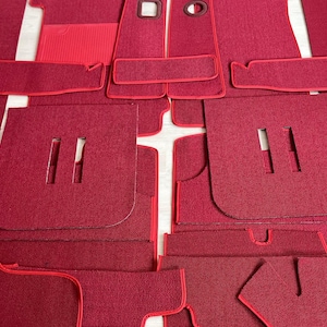 Puede incluir: Un juego de alfombrillas de coche rojas con ribete rojo. Las alfombrillas están hechas de un material suave y mullido y están diseñadas para adaptarse a los contornos del suelo del coche.