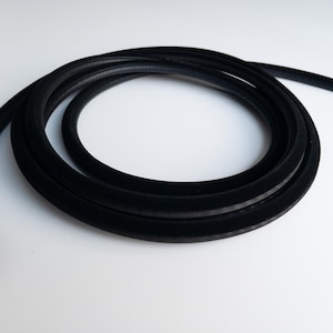 May include: A coiled length of black rubber weather stripping. The weather stripping has a soft, velvety texture and a U-shaped profile. It is designed to seal gaps and prevent drafts. The material is flexible and appears to be new.