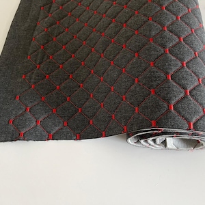 May include: A close-up of a gray fabric with red diamond-shaped stitching. The fabric is rolled up and the stitching is visible on the edges.