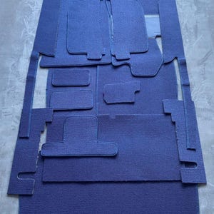 Puede incluir: Un juego de alfombrillas para coche azules de diferentes formas y tamaños. Las alfombrillas están hechas de un material suave y mullido y tienen un borde azul oscuro.