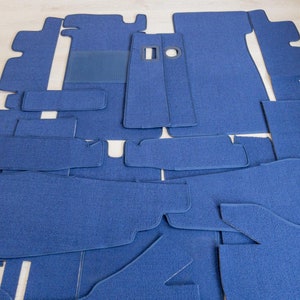 May include: A set of blue carpet pieces designed to fit the interior of a car. The pieces are cut to different shapes and sizes to cover the floor.