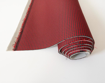 May include: A roll of red and black checkered fabric. The fabric is folded and rolled up, with the edges of the fabric visible.