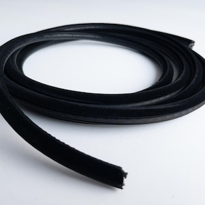 May include: A coiled length of black rubber weather stripping with a velvety texture. The flexible material is designed to seal gaps and prevent drafts. The product is shown against a white background.