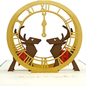 Elegante biglietto pop-up 3D con orologio e renna di Buon Natale. Un delizioso biglietto di auguri regalo per bambini, amici, familiari e persone care. 15 cm x 15 cm.