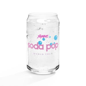 May include: A clear glass soda can-shaped glass filled with ice and a clear liquid. The glass has the words "Saja Boys" and "soda pop" in pink, with blue bubble graphics. The words "WORLD TOUR" are below the "soda pop" text.