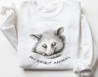 May include: White sweatshirt featuring a grey and white illustration of a possum sleeping with the text "My Spirit Animal" printed on the front.