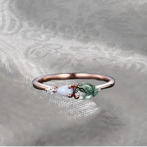 May include: A rose gold ring with a green moss agate, a white opal, and a small clear stone.