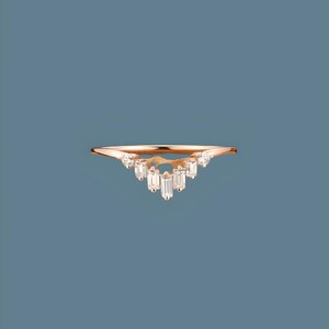 May include: A delicate gold ring with a V-shaped band adorned with small, clear baguette-shaped diamonds.