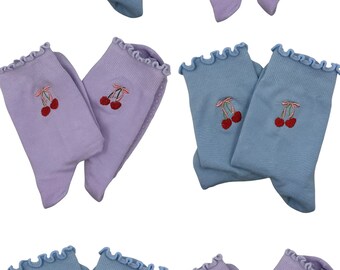 Puede incluir: Seis pares de calcetines con un diseño de cereza bordado. Tres pares son de color azul claro y tres pares son de color lavanda.