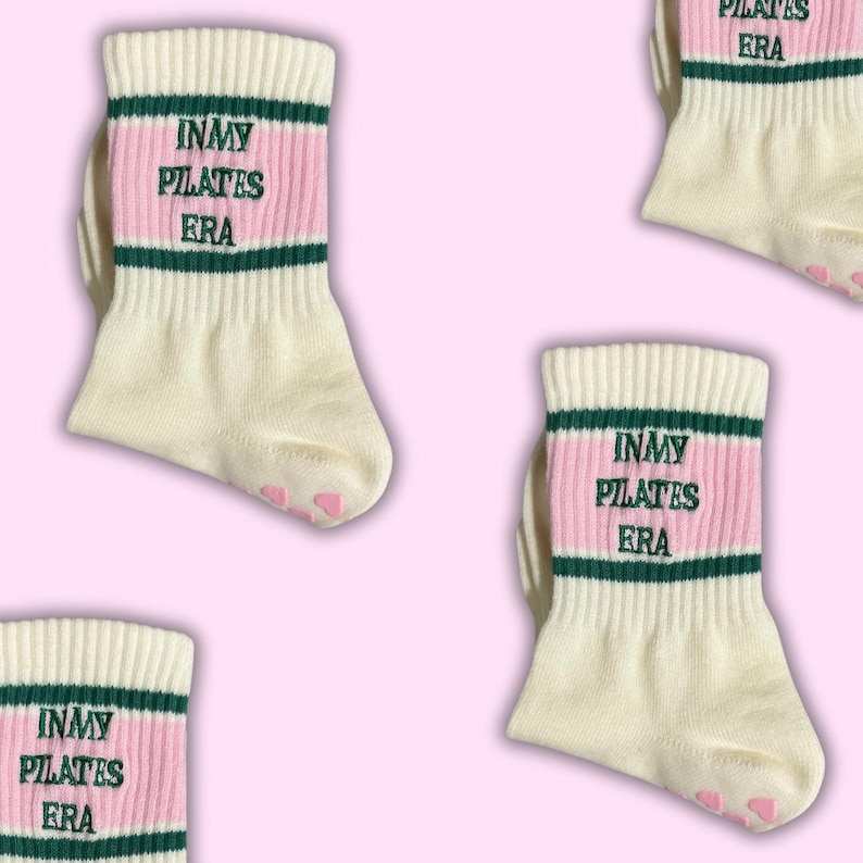 May include: White socks with pink and green stripes. The socks have the text "In My Pilates Era" embroidered on them.